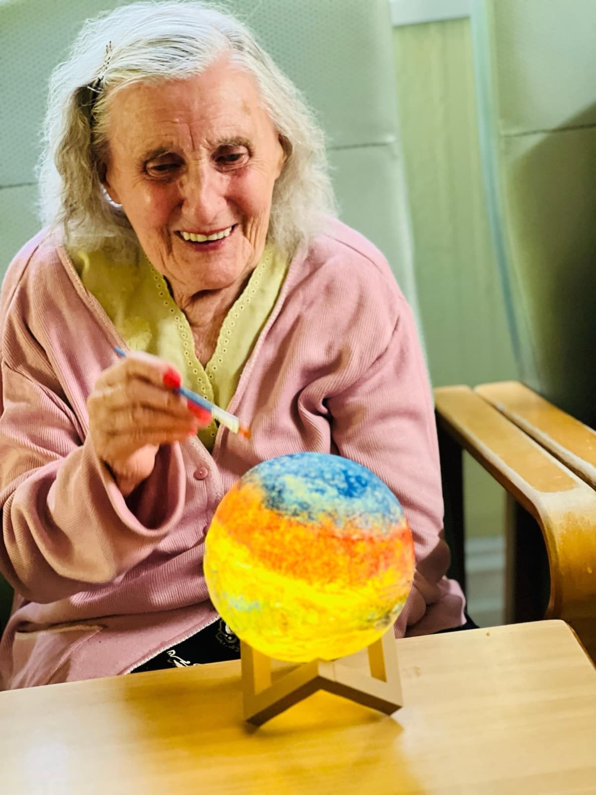 A resident painting a round lamp at a table