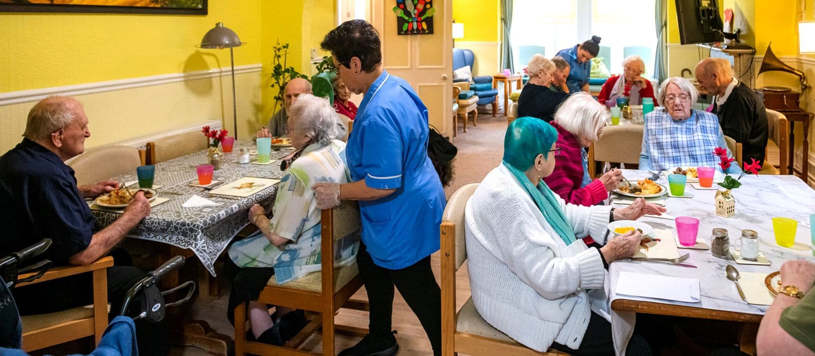 Residents having lunch together in the dining room while a carer serves