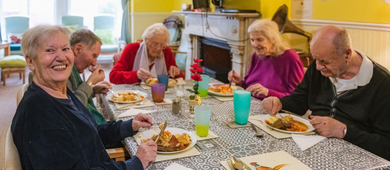 Residents smiling over lunch at the dining table